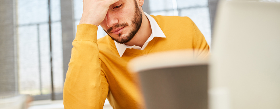 Junger Mann als Geschäftsmann im Büro denkt über ein schwieriges Problem nach