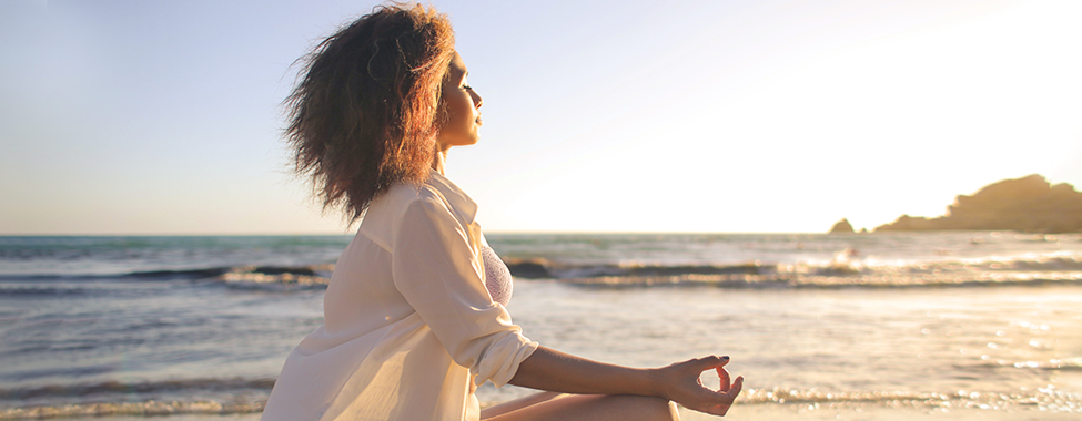 Woman-Meditating-on-Beach-for-Vacation-Mental-Health