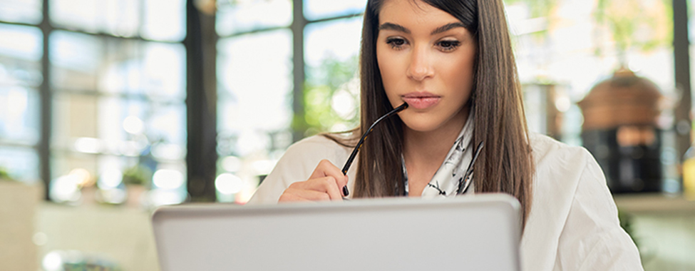 Beautiful caucasian elegant businesswoman sitting in cafe, holding eyeglasses and using laptop.