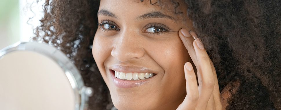 Portrait of beautiful mixed-race woman applying cosmetics on her face